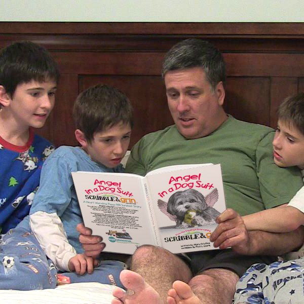 Dad and 3 boys reading Angel in a Dog Suit in bed